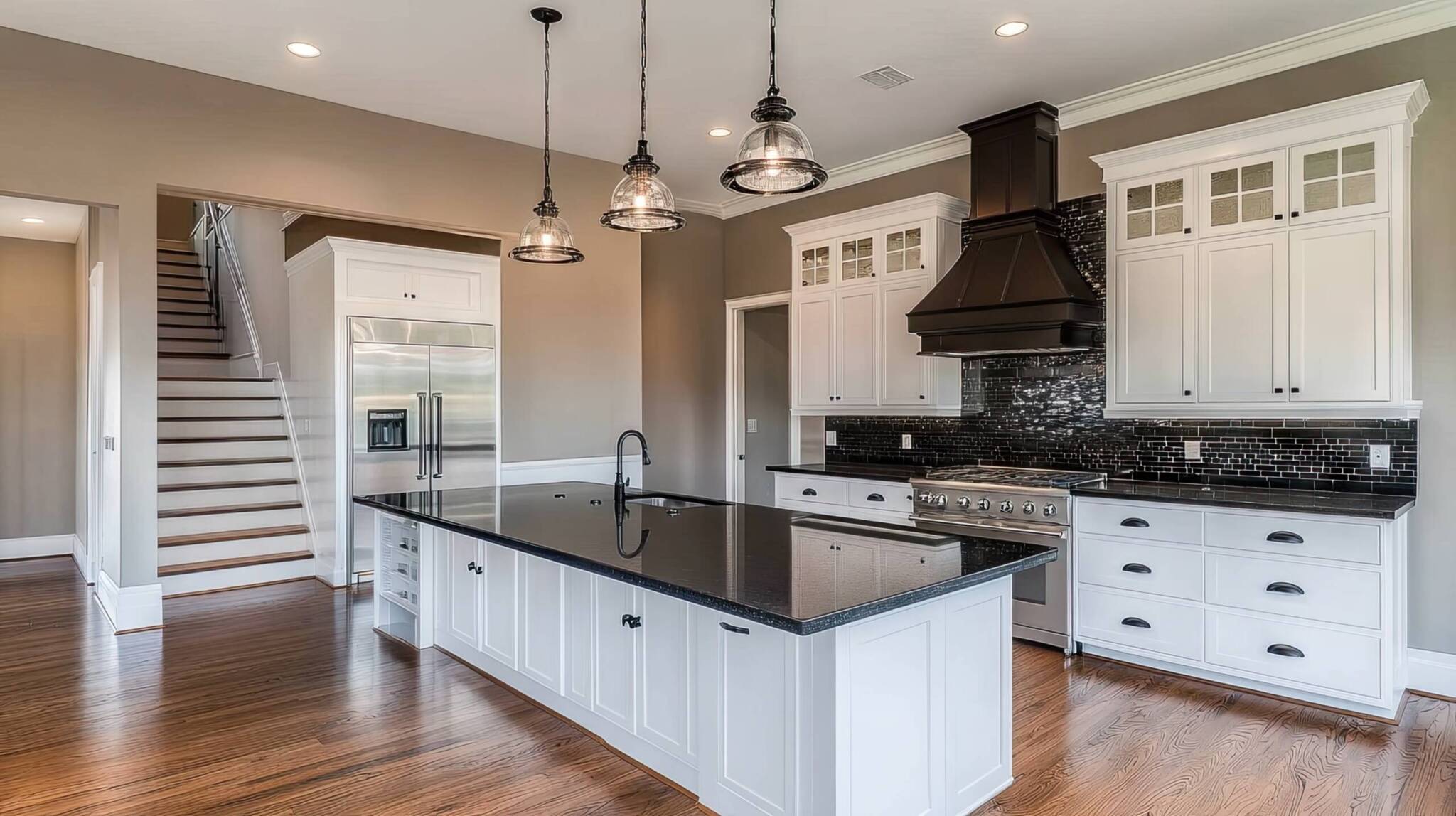 A spacious, modern kitchen with white cabinetry and a dark granite island.